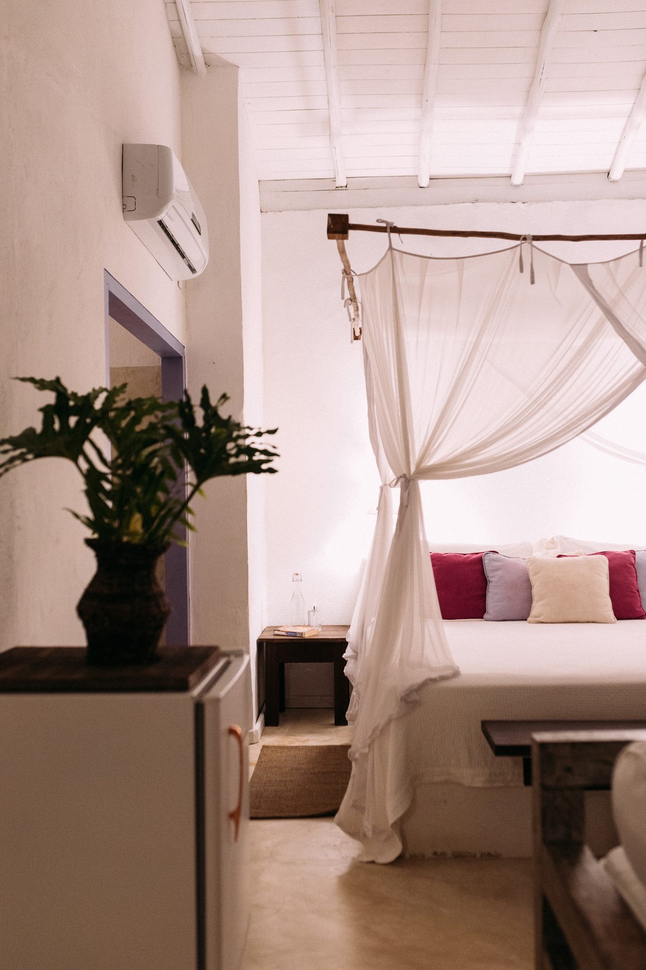Quarto do Bangalô Lilás com parede lilás, planta e almofadas coloridas